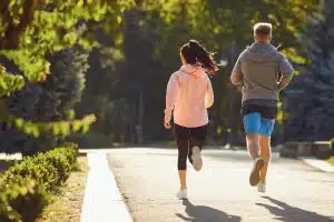 a man and a woman are running along the city street in the morning.